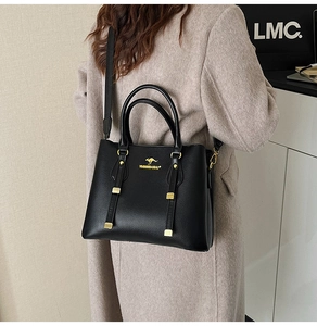Side view of black pebble leather tote bag featuring gold kangaroo logo and hardware