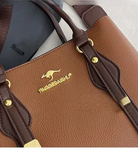 Detail of lychee pattern leather tote with golden kangaroo logo and metal studs