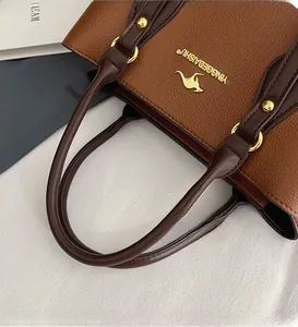 Close-up of brown lychee grain leather tote with gold logo and round handles
