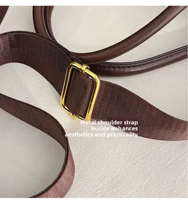 Detail of golden adjustable metal buckle and dark coffee strap on fashion handbag