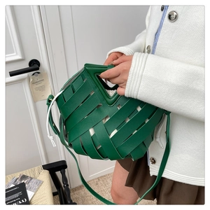 Dettaglio della borsa intrecciata verde con sacchetto bianco e manico a V elegante