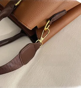 Detail of high-quality golden metal hook and brown lychee grain leather on a tote bag