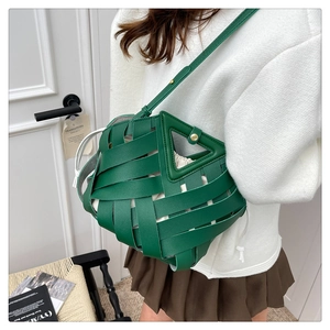 Dettaglio borsa a secchiello in pelle intrecciata verde scuro con sacchetto crema