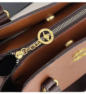 Detail of smooth golden zipper and metal kangaroo logo puller on brown lychee leather bag