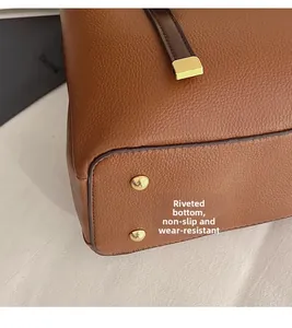 Macro shot of brown pebble leather bag base with protective gold metal rivets and stitching