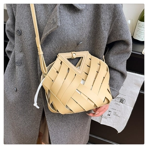 Dettaglio ravvicinato di una borsa a secchiello in pelle intrecciata con manico a triangolo