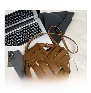 Borsa a tracolla intrecciata marrone con fodera a coulisse accanto ad accessori