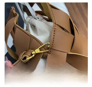 Dettaglio ravvicinato della texture in pelle intrecciata marrone con gancio in metallo oro