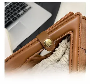 Dettaglio borsa in pelle intrecciata marrone con manico a triangolo e chiusura dorata