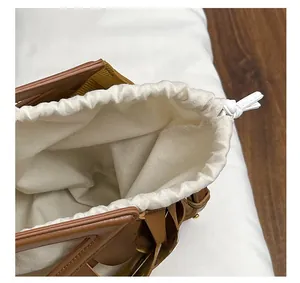 Dettaglio della borsa intrecciata in pelle marrone con chiusura a coulisse in tela beige