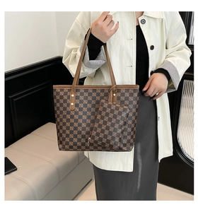 Detail of checkered tote bag set with golden hardware and matching pouch hanging