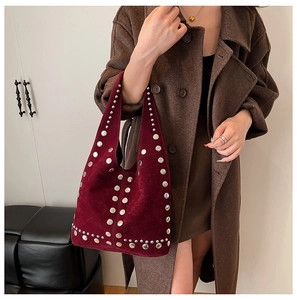 Détail du sac sous le bras en daim bordeaux avec clous argentés et style punk chic