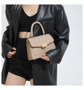 Detail of light brown handbag with quilted flap, crocodile texture, and gold buckle