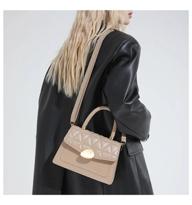 Close-up of quilted beige handbag with designer gold metal buckle and leather handle