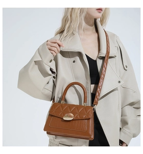 Detail of brown crocodile pattern small square bag showing quilted flap and golden buckle