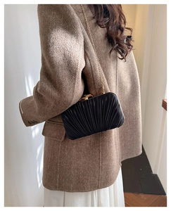 Detail of a black pleated satin evening clutch bag with an elegant gold chain strap
