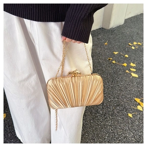 Detailed view of golden pleated evening clutch with elegant metallic twig clasp and chain