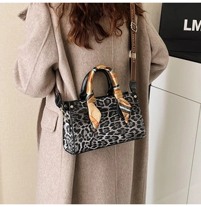 Detail of leopard print handbag featuring a silk scarf handle and wide canvas strap