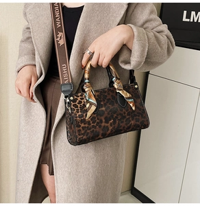 Detail of leopard print handbag with silk scarf handle and wide lettered strap