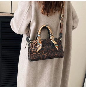 Detail of leopard print handbag with silk scarf handle and wide branded fabric strap