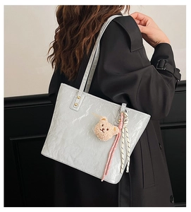 Close-up of light grey tote bag featuring unique pleated texture and cute bear charm