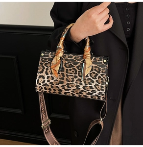 Close-up of leopard print handbag with silk scarf handle and wide branded fabric strap