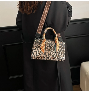 Close-up of leopard print handbag with silk scarf handle and wide fabric strap