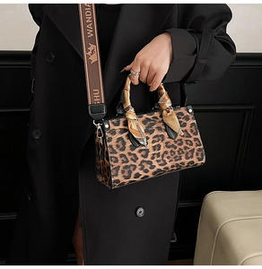 Detail of leopard print crossbody bag with branded wide strap and silk scarf on handle