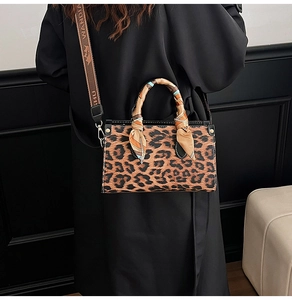 Detail of leopard print handbag featuring a silk scarf handle and wide branded strap