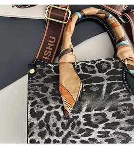 Close-up of leopard print handbag with colorful silk scarf handle and wide branded strap