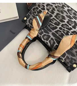 Detail of leopard print handbag with colorful striped silk scarf wrapped around handle