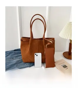 Detailed size comparison of the large suede tote bag and matching pouch with a smartphone