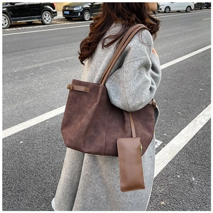 Street style view of a large brown suede tote bag with a matching small pouch detail
