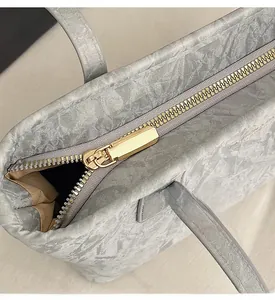 Detailed macro shot of smooth gold metal zipper and grey marble textured leather bag