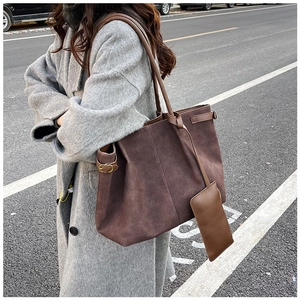 Detail of suede tote bag side with vintage brass buckle and detachable hanging pouch