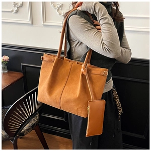 Detail of brown suede tote bag featuring a matching inner pouch and adjustable side straps