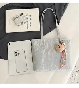 Flat lay of gray tote bag showing large capacity with tablet, phone, and plush charm