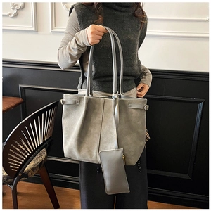 Close-up of grey suede tote bag with side buckles and matching mini pouch for daily commuting