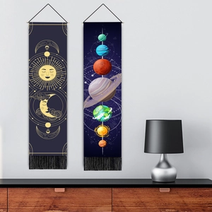 Modern celestial sun and moon tapestry with black fringes hanging in a minimalist living room