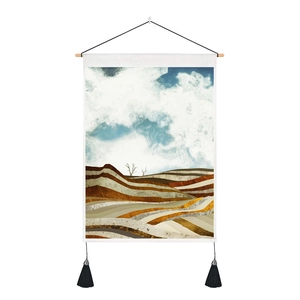Abstract landscape wall hanging featuring golden hills and blue clouds with elegant tassels