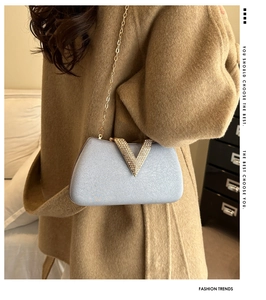 Detail of light blue sequined evening clutch with V-shaped rhinestone buckle and gold chain