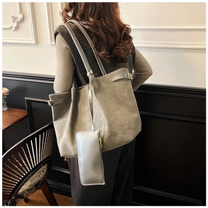 Detail view of large grey suede tote bag with matching inner pouch on model shoulder
