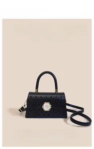 Détail d'un sac à main en cuir noir matelassé avec des clous et un fermoir doré rond