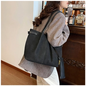 Detail of a black suede tote bag with slim shoulder straps and a matching coin purse