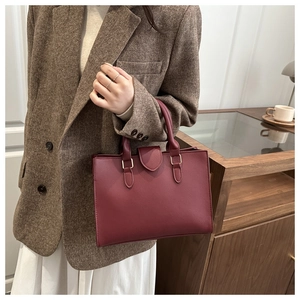 Detail view of burgundy leather tote bag with elegant golden hardware and top handle