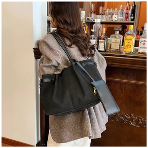 Detail of black suede tote bag with removable pouch and adjustable side buckle strap