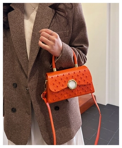 Détail du sac bandoulière orange avec texture à pois 3D et boucle ronde en métal