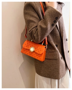 Détail du sac à bandoulière orange clouté avec fermoir perle sur une veste en tweed chic