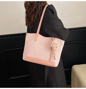 Pink pleated tote bag shown on shoulder with cute plush bear charm detail