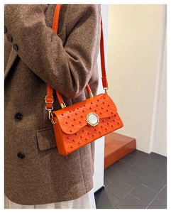 Détail du sac orange avec clous 3D et fermoir perle sur cuir synthétique de qualité
